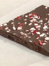 Load image into Gallery viewer, Close up of one piece of peppermint toffee nib brittle with ground pieces of peppermint candies on top of chocolate