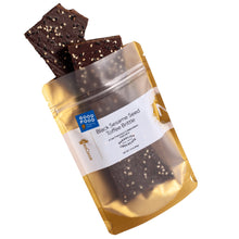 Load image into Gallery viewer, Sesame brittle pouring out of 3oz sized bag with label stating “Black Sesame Seed Toffee Brittle” collaboration with Dandelion Chocolate and NeoCocoa logo.