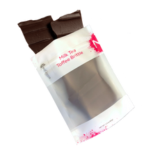 Load image into Gallery viewer, Milk Tea brittle pouring out of 3oz sized bag with label stating “Milk Tea Toffee Brittle” and a pink NeoCocoa logo.